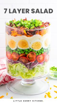 a layered salad in a glass dish on top of a table with the words 7 layer salad