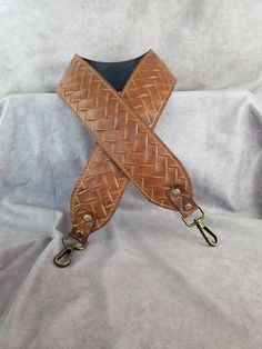 a brown leather belt with brass hardware on a white cloth background, close up view