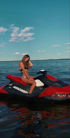 a woman sitting on top of a red and black jet ski