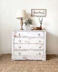 an old white dresser with two lamps on top and a sign above it that says farmhouse