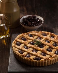 an image of a pie with olives in the background on a wooden table top