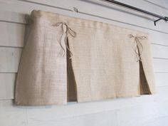 a pair of beige curtains hanging on the side of a white wall with wood planks