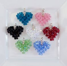 six different colored heart shaped charms on a white plate