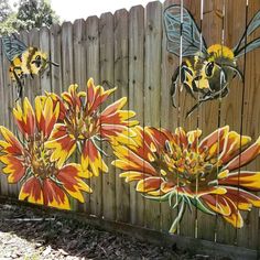 a fence with some flowers painted on it and two bees sitting on top of the flowers