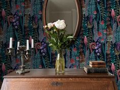 a vase filled with flowers sitting on top of a wooden dresser next to a mirror