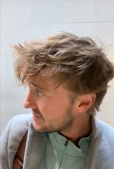 a man with his hair in the wind looking off to the side while wearing a jacket