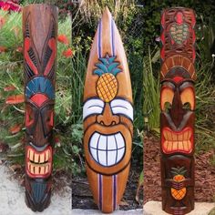 three wooden tiki masks sitting next to each other in front of plants and flowers