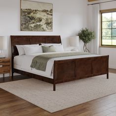 a large bed sitting in a bedroom on top of a wooden floor next to a window