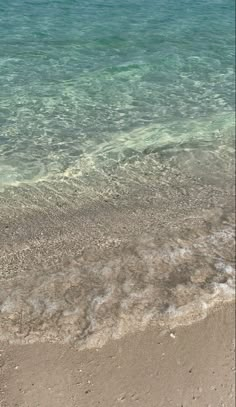 the surfboard is laying on the beach by the water