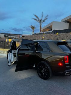 a black and white car with its doors open in front of a building at night