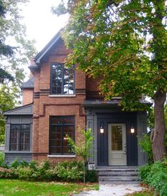 a brick house with two story windows and an entry way leading to the front door