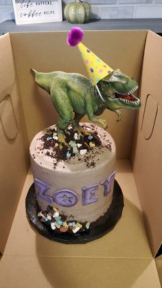 a birthday cake in the shape of a t - rex with a party hat on top