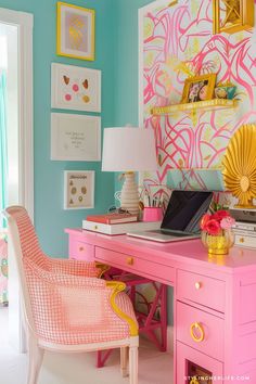 a desk with a laptop on top of it next to a pink and yellow chair