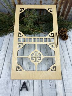 a wooden frame sitting on top of a table next to a pine cone and scissors