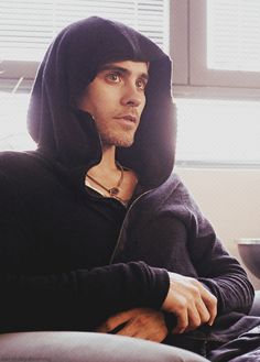 a man in a hoodie sitting on a couch