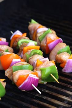 several skewers of meat and vegetables cooking on a grill