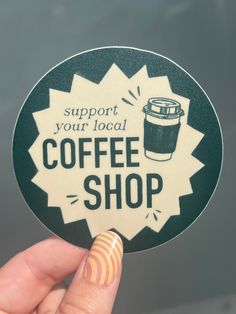 someone holding up a sticker that says support your local coffee shop