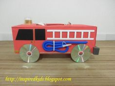 a toy firetruck with cd's on the front and back wheels, sitting on a wooden floor