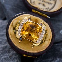 a fancy ring with an orange topaz surrounded by white and yellow diamond accents in a velvet case