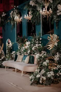 a couch sitting in front of a blue wall with flowers and greenery on it