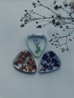 three pieces of glass sitting on top of a white table next to some dried flowers