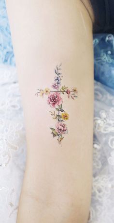 a cross tattoo with flowers on it