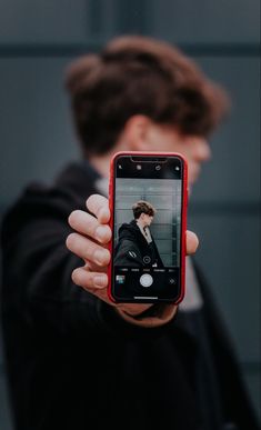 a person holding up a cell phone to take a photo with their face on the screen