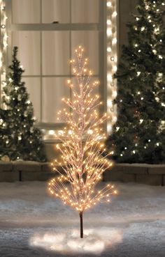 a lighted christmas tree in front of a window