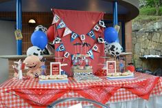 a table topped with cake and balloons in front of a red wall