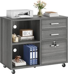 a bookcase with two drawers and three file cabinets on wheels next to a flower vase