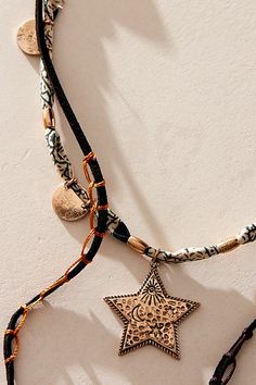 Get that effortlessly layered look with this multi-strand necklace, featured in a mixed-material design with a cascading lariat, beaded accents, and star pendants. **Features:** Layered style, lariat design, suede and textile chains, knotted details, mixed beads, star pendants, adjustable clasp closure | Dandelion Lariat Necklace by Free People in Black Bohemian Necklace With Star Charm For Festivals, Bohemian Star Charm Necklace For Festivals, Bohemian Festival Necklaces With Star Charm, Bohemian Jewelry With Star Charm, Festival Multi-strand Layered Necklace, Gold Lariat Necklace, Layered Style, Multi Strand Necklace, Tan Suede