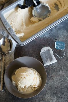 two scoops of ice cream sit in a bowl next to spoons and spatulas