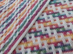 the blanket is made up of multicolored crocheted squares and has been folded over