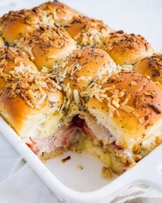 a white casserole dish filled with ham and cheese sliders on top of a towel