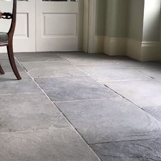 a chair sitting in front of a door on top of a stone floor next to a doorway