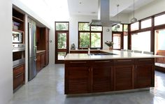 a large kitchen with wooden cabinets and stainless steel appliances in the center, along with lots of windows