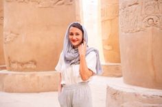 a woman is standing in front of some pillars talking on her cell phone and smiling