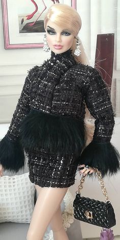 a barbie doll wearing a black and white dress with fur trimmings, holding a handbag