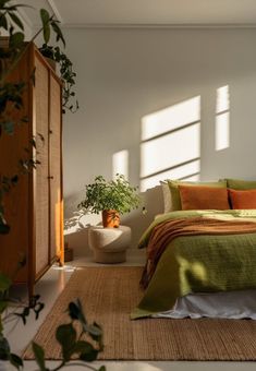 a bedroom with green and orange bedding in the sun shining through the window blinds