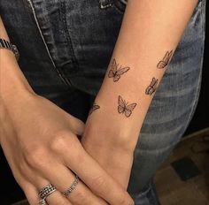 a woman's arm with butterfly tattoos on her left wrist and the other hand