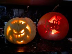 two pumpkins with carved faces and cats on them