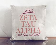 a pillow with the words delta delta on it sitting on top of a wooden shelf