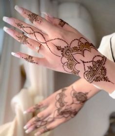 two hands with henna tattoos on them