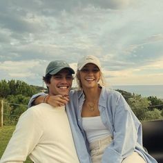 a man and woman sitting on the back of a pickup truck smiling at the camera