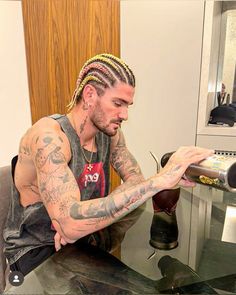 a man with dreadlocks sitting at a table and looking at his cell phone