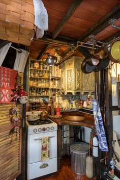 an old fashioned kitchen with lots of pots and pans hanging from the ceiling,