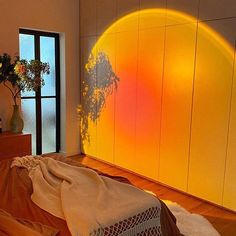 the sun is shining brightly on the wall behind a bed with an orange comforter