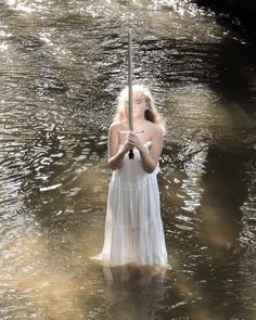 a woman is standing in the water holding an umbrella