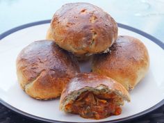 four rolls filled with meat sitting on top of a white plate