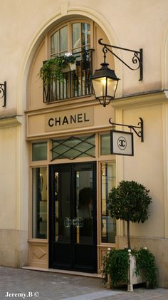 the entrance to a chanel store with potted plants on the balcony and lampposts